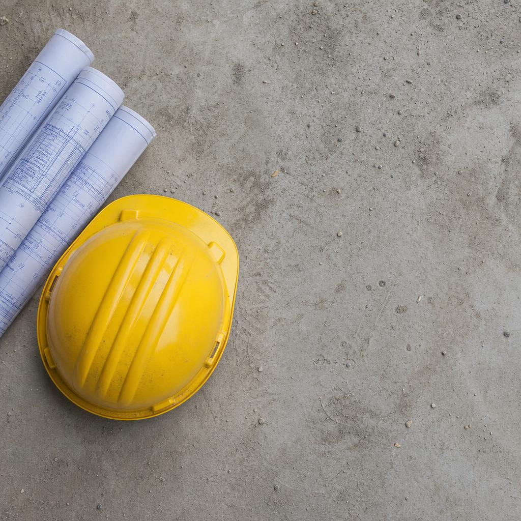 Hard hat and blueprints on concrete floor